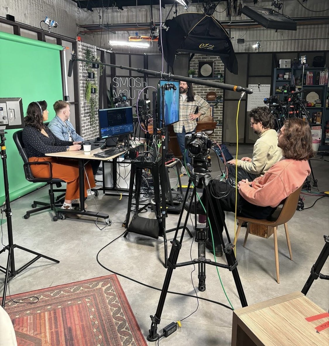 behind the scenes of smosh games recording set with shayne topp and amanda lehan canto playing in front of a green screen, while alex tran and spencer agnew observe from across them